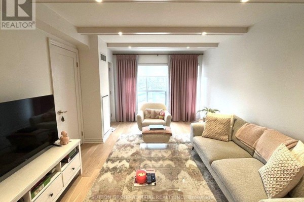 Living room with sofa, armchair, and coffee table in front of a large window with pink drapes. - 301 - 1174 Yonge Street, Toronto