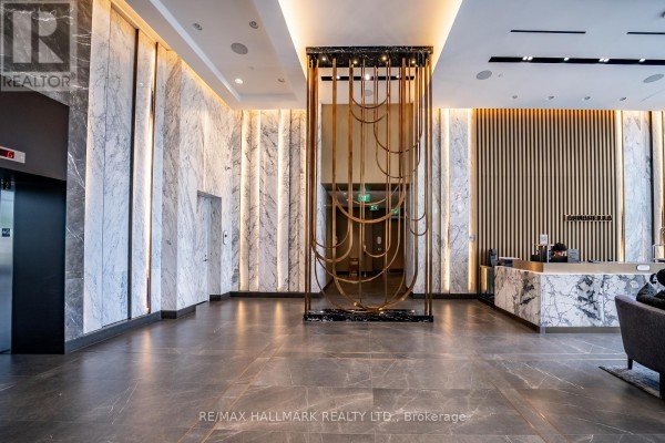 Apartment building lobby with marble walls, brass accents, and tiled floor. - 301 - 118 Merchants' Wharf, Toronto