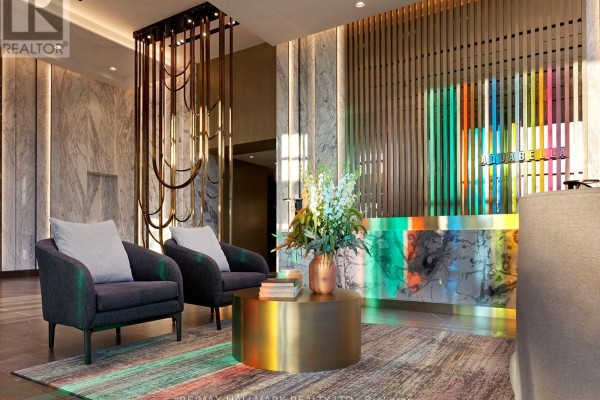 Lobby seating area with two chairs, a coffee table, and a reception desk. - 301 - 118 Merchants' Wharf, Toronto