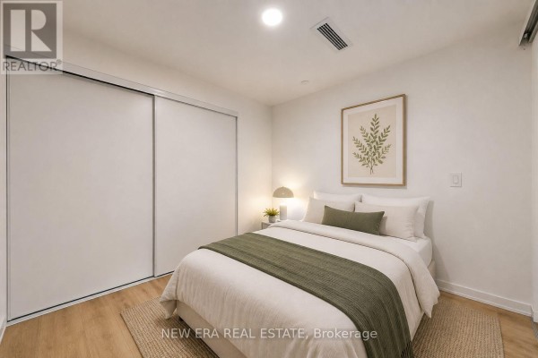 A compact bedroom configured as a home office with a bed, white desk, and dual monitors. - 301 - 150 Logan Avenue, Toronto