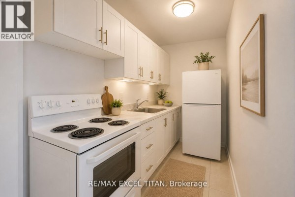 Compact kitchen with white cabinets, grey countertop, electric stove, and stainless steel refrigerator. - 301 - 165 Cosburn Avenue, Toronto