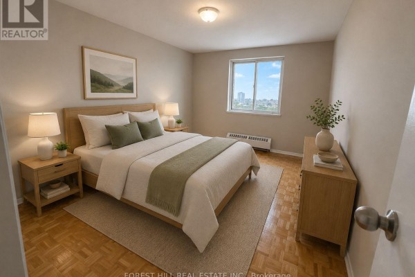 Second bedroom with a queen bed, wooden furniture, beige walls, and a window overlooking the city. - 301 - 165 Kennedy Road, Brampton