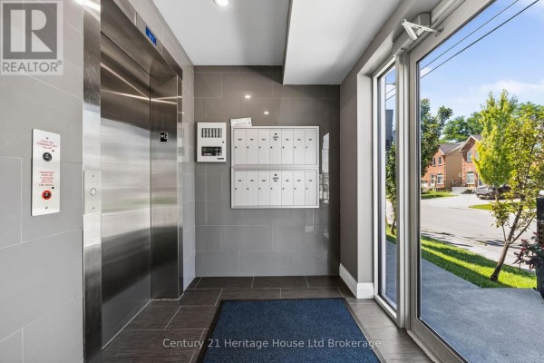 Apartment building lobby with a silver elevator, mailboxes, and a glass entrance door. - 301 - 34 Brock Street, Woodstock