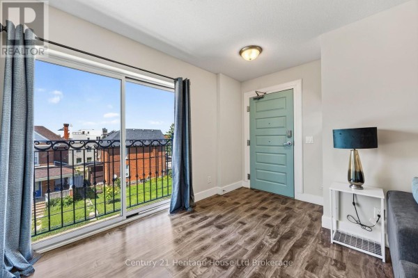 Apartment interior with a large sliding glass door showing a balcony and exterior view, light teal door. - 301 - 34 Brock Street, Woodstock