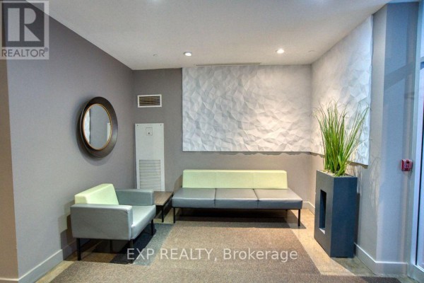 Building lobby with gray walls, a textured wall panel, and two modern couches. - 301 - 383 Cumberland Street, Ottawa