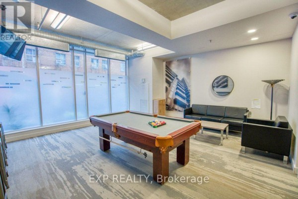 Common area with a pool table, seating, and frosted windows with building graphics. - 301 - 383 Cumberland Street, Ottawa