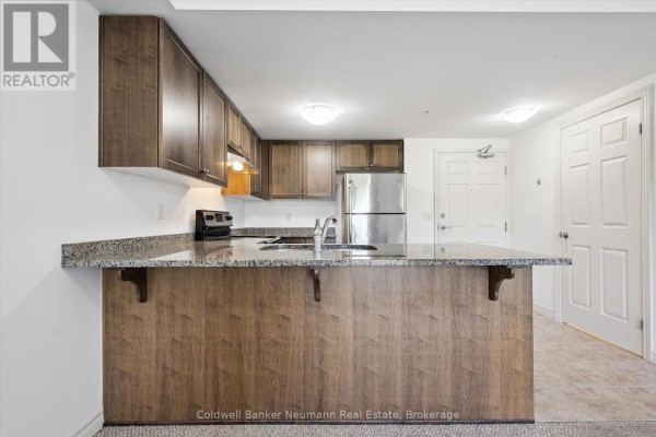 View of the kitchen with a peninsula, stainless steel refrigerator, and white doors. - 301 - 45 Kingsbury Square, Guelph