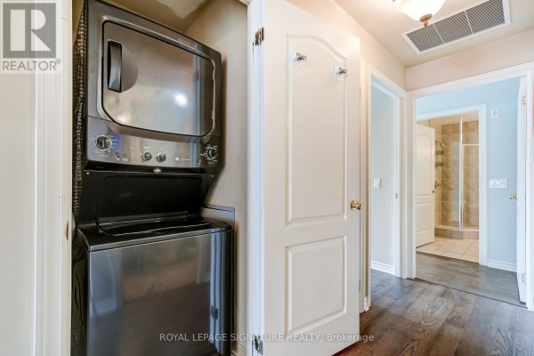 Stacked washer/dryer & hallway with wood floors - 301 - 483 Faith Drive Mississauga