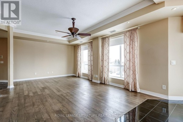 Spacious living room with hardwood floors, tray ceiling fan, and large windows - 301 - 483 Faith Drive Mississauga