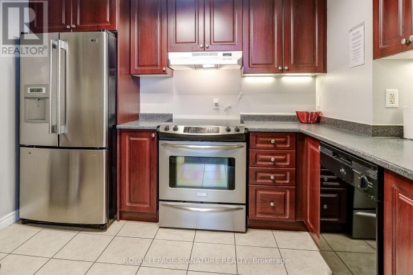 Kitchen with dark wood cabinets, stainless steel appliances, and granite counters - 301 - 483 Faith Drive Mississauga