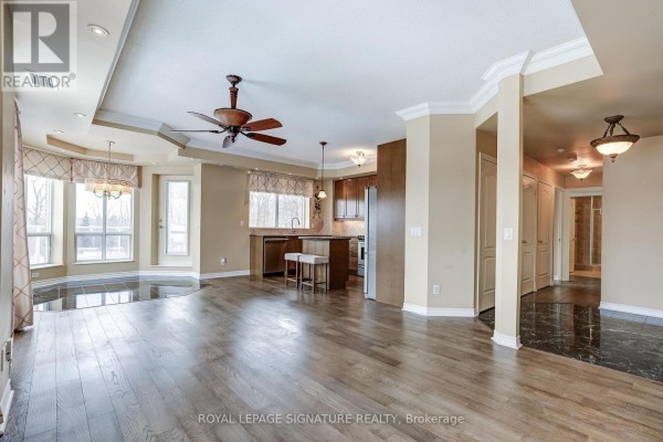 Living room with tray ceiling, kitchen island, hardwood floors, and bay windows - 301 - 483 Faith Drive Mississauga