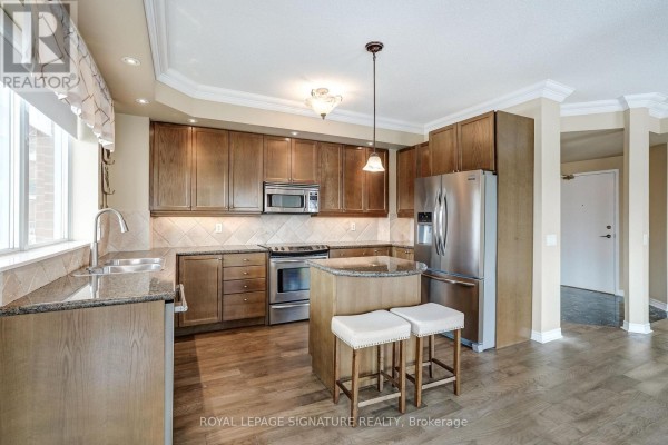 Modern kitchen with stainless steel appliances, island, and granite counters - 301 - 483 Faith Drive Mississauga