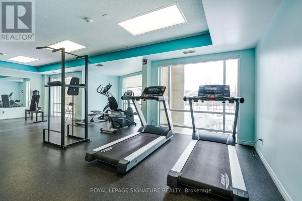 Fitness room with treadmills, elliptical, weight rack, and large windows - 301 - 483 Faith Drive Mississauga