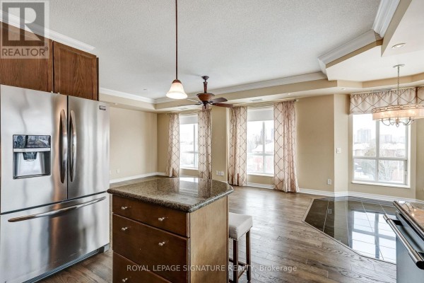 Stainless steel refrigerator, island with granite countertop, ceiling fan, and chandelier - 301 - 483 Faith Drive Mississauga