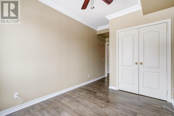 Bedroom with dual closet doors, ceiling fan, and wood laminate floors - 301 - 483 Faith Drive Mississauga