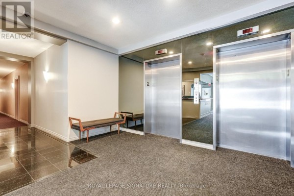 Elevators with mirrored walls and bench seating in a hallway - 301 - 483 Faith Drive Mississauga