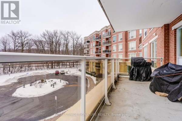 Balcony with glass railing, covered grills, view of snowy parking lot and brick building - 483 Faith Drive Mississauga