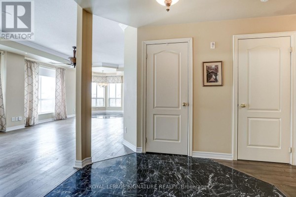 Hallway with marble flooring, two doors, and view into open-concept living space with large windows - 301 - 483 Faith Drive Mississauga
