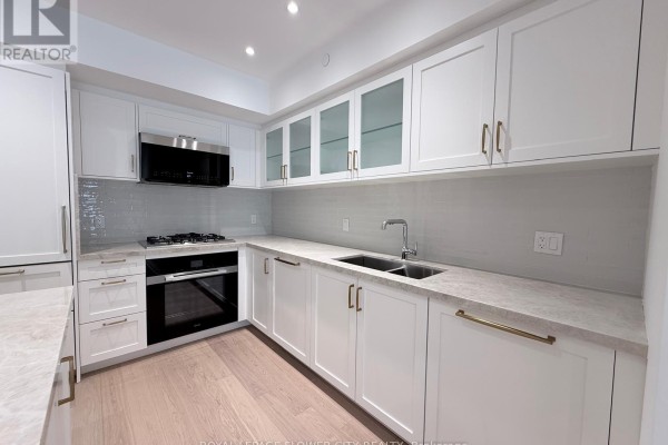White contemporary kitchen with a grey marble countertop, stainless steel appliances, and light oak floors. - 301 - 505 Glencairn Avenue, Toronto