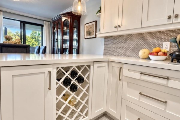 Kitchen island with a built-in wine rack, white shaker cabinets, and quartz countertops. - 301 - 55 Carscadden Drive, Toronto