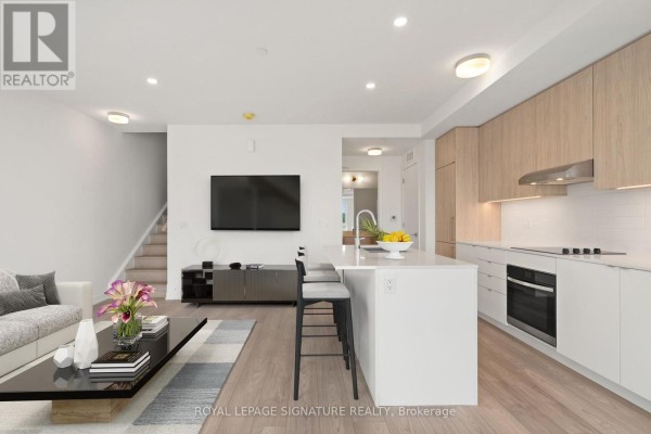 Kitchen with white countertops and backsplash, light wood cabinetry, and an island with bar stools. - 301 - 67 Saigon Drive, Richmond Hill