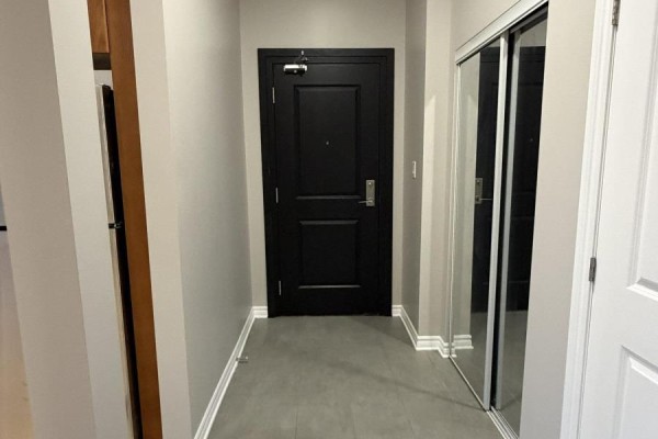 Apartment hallway with a black door, grey floor, and mirrored closet doors. - 301 - 682 Churchill Avenue N, Ottawa