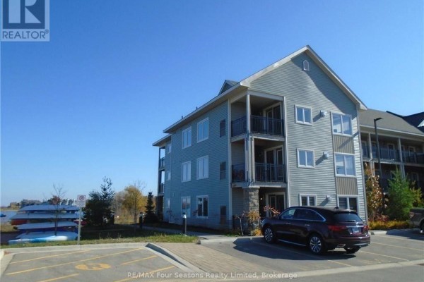 Side view of the condo building with balconies, windows, and a parking lot with a car. - 301 - 7 Anchorage Crescent, Collingwood