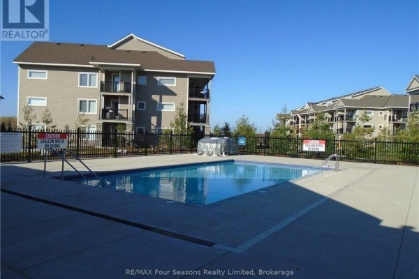 Exterior view of the condo building with a fenced swimming pool and pool deck in the foreground. - 301 - 7 Anchorage Crescent, Collingwood