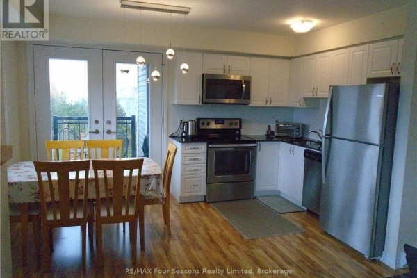Kitchen and dining area with white cabinets, stainless steel appliances, and a table with chairs. - 301 - 7 Anchorage Crescent, Collingwood