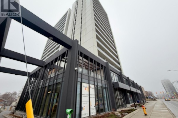 Side view of the apartment tower featuring grey panels and black accents, with a generator unit. - 301 - 741 King Street W, Kitchener