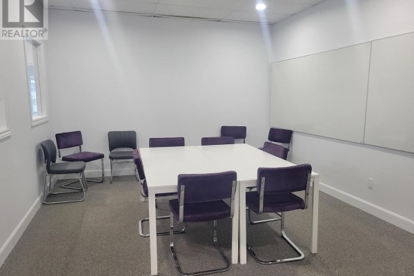 Conference room with a white table, purple chairs, and a whiteboard on the wall. - 301 - 80 Queen Street, Kingston