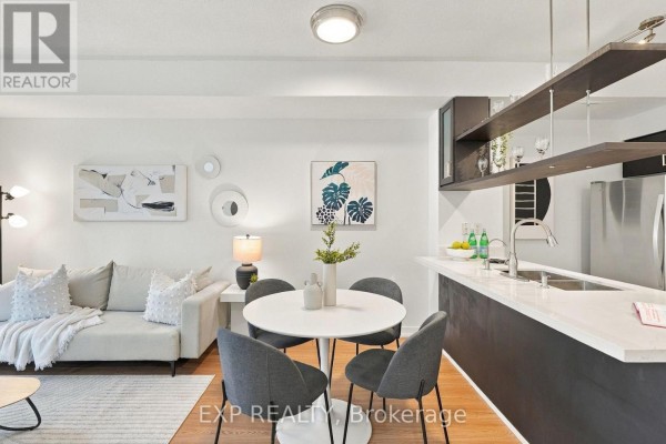 Dining table with four chairs next to the open kitchen island with white countertop. - 301 - 9 Spadina Avenue, Toronto