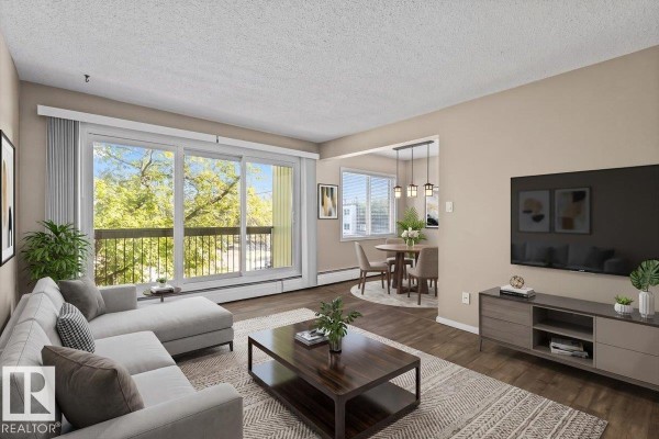 Living room with a sectional sofa, coffee table, dining area, and large sliding glass door. - #301 11465 41 Av Nw, Edmonton