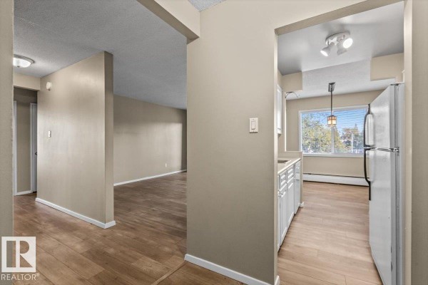 View from the hallway into the living room and a small kitchen area. - #301 11465 41 Av Nw, Edmonton