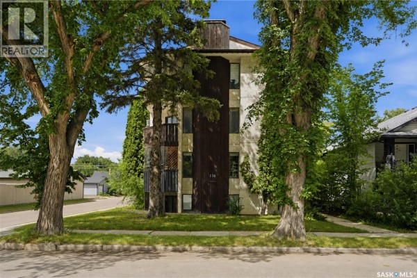 Side view of apartment building with beige stucco exterior, dark wood paneling, and balconies. - 301 116 111th Street, Saskatoon
