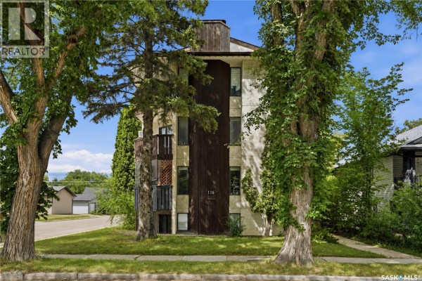 View of apartment building with balconies, green trees, and a corner lot. - 301 116 111th Street, Saskatoon