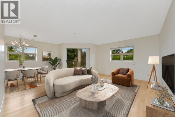 Living and dining area with light wood floors, a curved sofa, and a glass sliding door. - 301 1694 Cedar Hill Cross Rd, Saanich