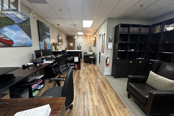 Office interior with desks, chairs, reception area, and large dark bookshelves. - 301 2609 Westview Drive, North Vancouver