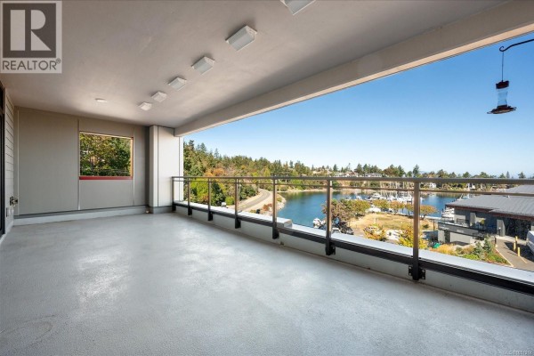 Spacious balcony with water view, boats, surrounding trees, and modern building structures. - 301 3529 Dolphin Dr, Nanoose Bay