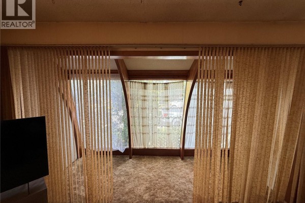 Interior view of large windows covered by vertical and sheer lace curtains. - 301 5th Avenue W, Kindersley