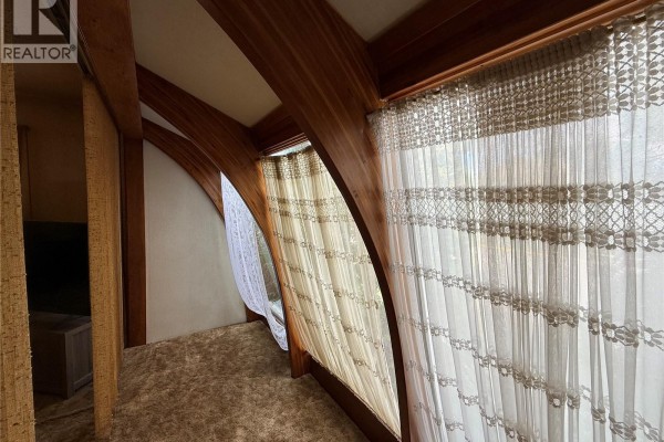Close-up of arched wooden beams and windows with textured lace curtains inside the house. - 301 5th Avenue W, Kindersley