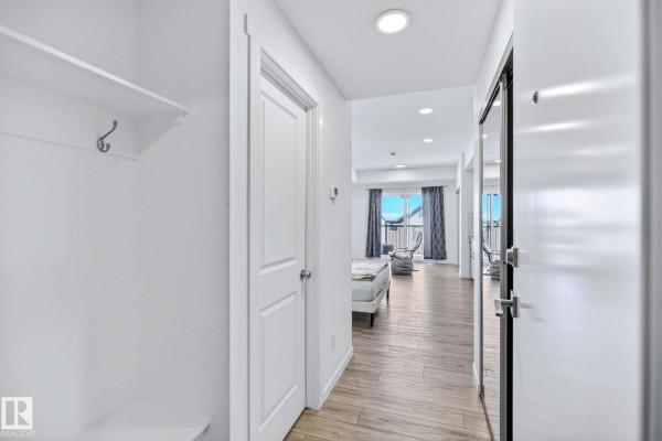 Open-concept living area with kitchen, stainless steel appliances, and seating area. - #301 864 Secord Bv Nw, Edmonton