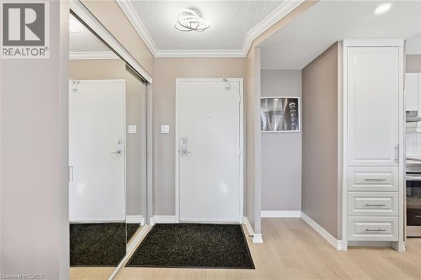 Apartment entrance hallway with mirrored closet, white door, and storage unit. - 301 Frances Avenue Unit# 705, Hamilton