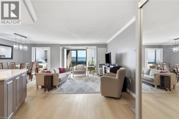 Living room with sofa, armchair, dining area, and balcony view. - 301 Frances Avenue Unit# 705, Hamilton