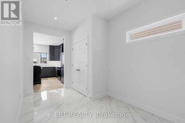 Hallway leading to modern kitchen with dark cabinets and marble tile - 301 Moonlight Drive Russell