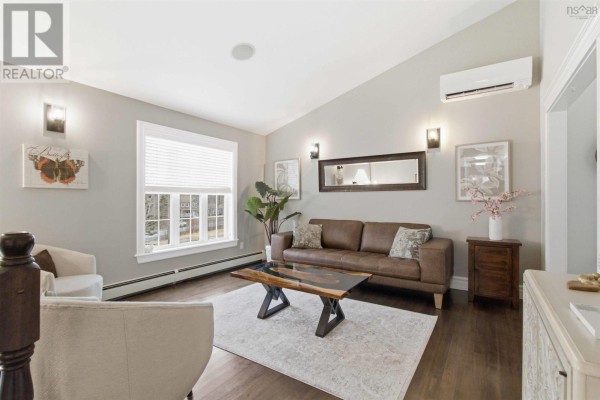 Living room with a brown leather sofa, white chairs, a wooden coffee table, and a large window. - 301 Preakness Crescent, Fall River