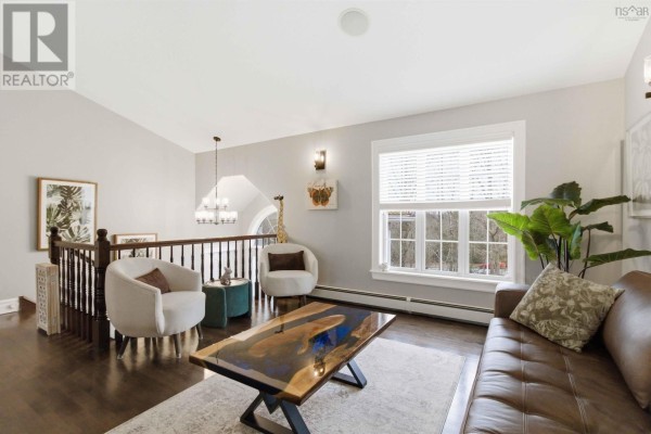 Living room with a brown leather sofa, two white chairs, a unique coffee table, and a large window. - 301 Preakness Crescent, Fall River
