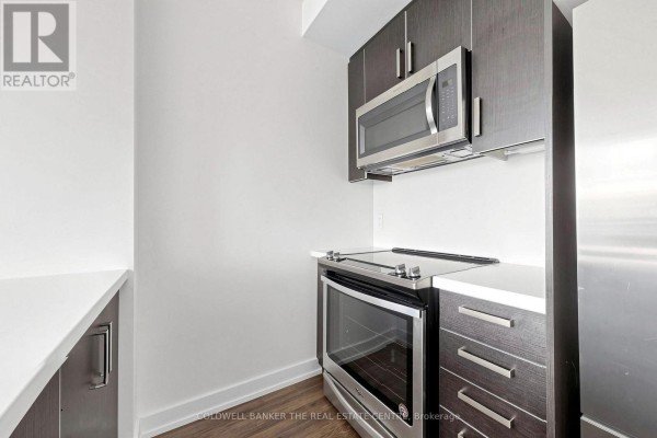 Close-up of stainless steel oven and microwave above a stovetop. - Unit #415 - 301 Sea Ray Avenue, Innisfil