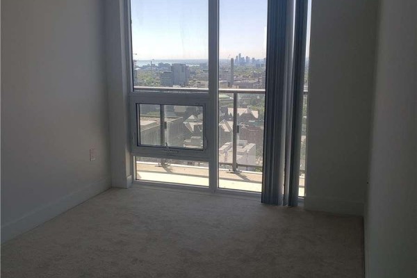 Empty bedroom with light grey carpet, white baseboards, and floor-to-ceiling windows with city views. - 3012 - 955 Bay Street, Toronto