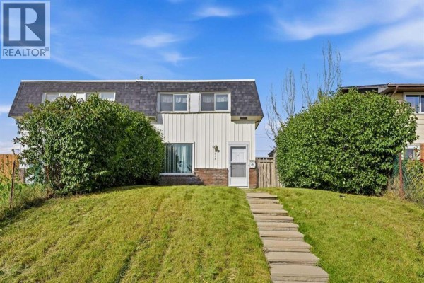 Front entrance of the duplex with a grass lawn and a stone pathway leading up. - 3012 Dover Crescent Se, Calgary